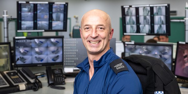 Detention Officer Raz Andrei smiling sitting with his computers behind him
