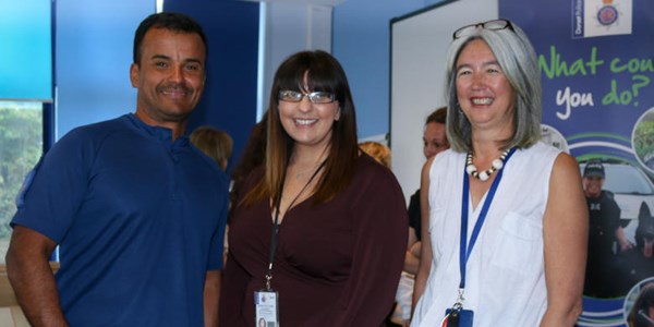 Three staff members stood in front of a stand