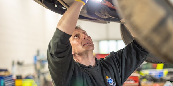 Mechanic working on underside of raised car