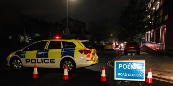 A police car on the street at night behind cones